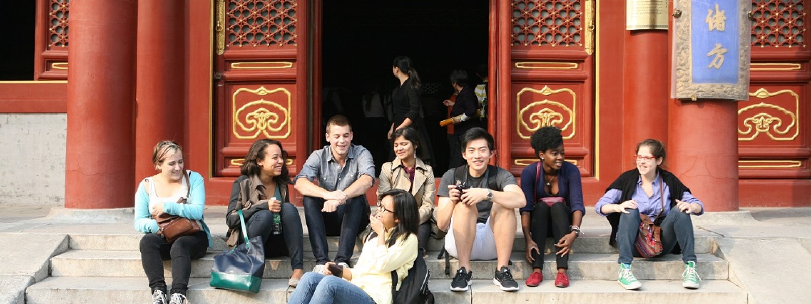 Eight students sit together on the steps of the temple.